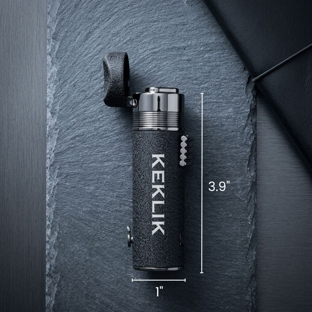 Black textured cigar lighter with "KEKLIK" engraved vertically, chrome dual-flame head, leather carrying loop, and measurement indicators showing 3.9 inches tall and 1 inch wide.