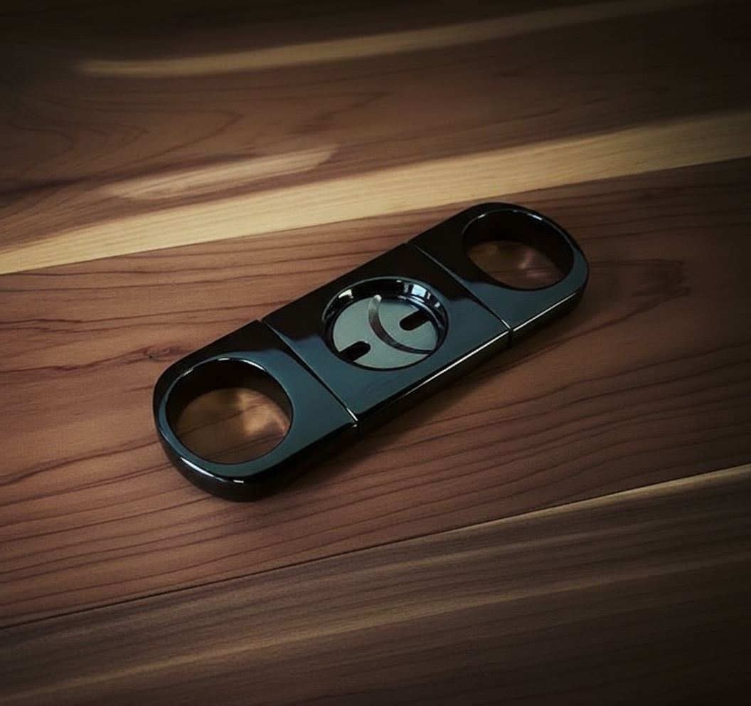 Gun metal double-blade guillotine cigar cutter with dual circular handles displayed on a wooden surface