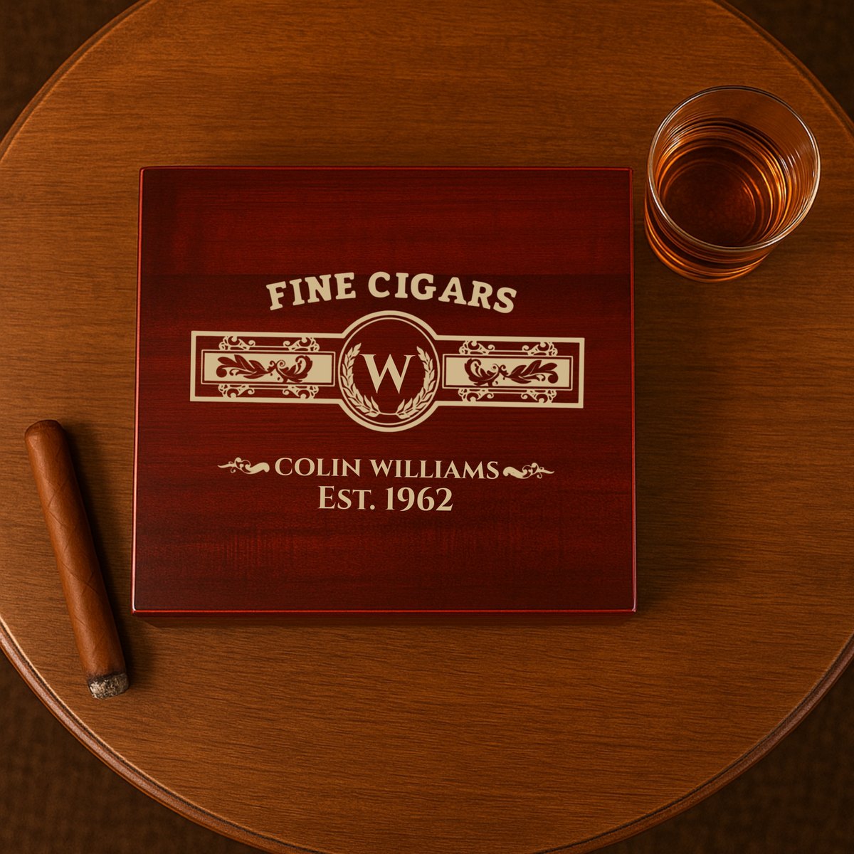 Dark red cedar humidor with cream engraving reading "FINE CIGARS," decorative monogram with sample initial "W," and "COLIN WILLIAMS EST. 1962," displayed on wooden table with cigar